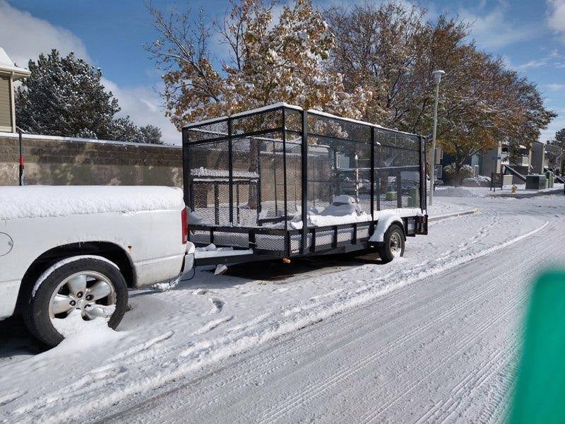 Dodge Ram with open mesh-sided trailer parked in snow